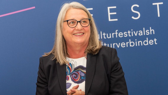 Dorit Stenke steht vor einer Werbewand für ein Kulturfestival © IMAGO Foto: penofoto