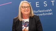 Dorit Stenke steht vor einer Werbewand für ein Kulturfestival © IMAGO Foto: penofoto