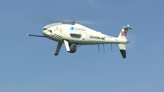 Die Drohne steht mit rotierenden Rotorblättern am Himmel. © NDR 
