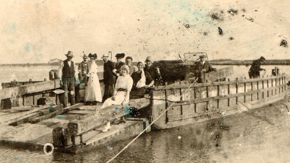 Ein altes Foto von einer Fähre. Darauf befinden sich mehrere Menschen, die in die Kamera lächeln. © Stadtarchiv Friedrichstadt / Museum "Alte Münze"  