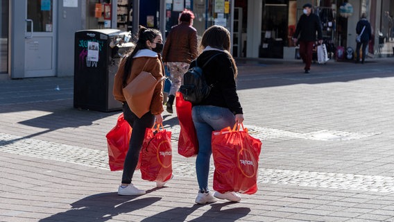 Zwei Personen mit Einkaufstaschen in der Holstenstraße in Kiel. © IMAGO / penofoto 