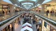 Menschen sind in einem weihnachtlich geschmückten Einkaufszentrum unterwegs. © NDR 