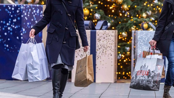 Menschen mit Einkaufstüten laufen durch eine weihnachtlich geschmückte Innenstadt. © Imago Images / Arnulf Hettrich Foto: Arnulf Hettrich