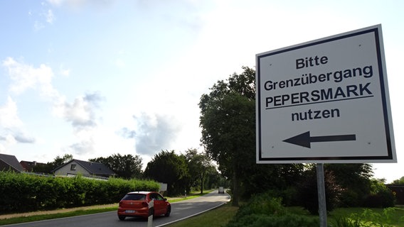 Auf einem Schild steht "Bitte Grenzübergang Pepersmark nutzen", dazu zeigt ein Pfeil in Richtung der Grenzstraße. © NDR Foto: Peer-Axel Kroeske