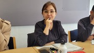 Nadja Elham mit Schreibutensilien an einem Tisch. © NDR Foto: Frank Goldenstein