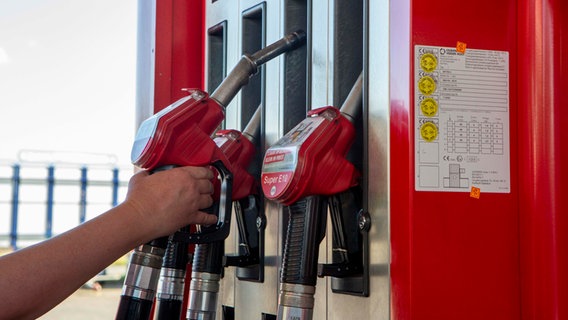 Eine Person greift nach einem Tankstutzen. © picture alliance Foto: picture alliance | Goldmann