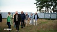 Eine Gruppe von Menschen laufen über ein Feld auf dem Solarpanel stehen. © NDR 