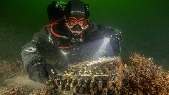Der Unterwasser-Archäologe Florian Huber begutachtet die gefundene Enigma © Christian Howe/submaris Foto: Christian Howe
