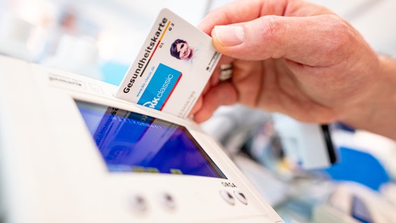 Ein Mitarbeiter einer Apotheke steckt eine Gesundheitskarte in ein Lesegerät. © picture alliance/dpa Foto: Fabian Sommer