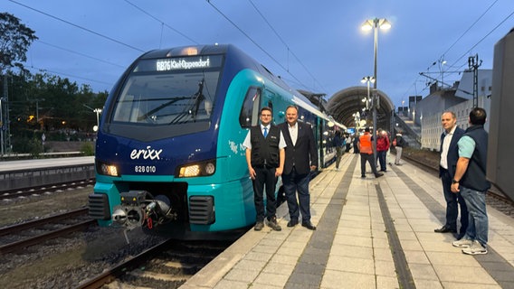 Am Kieler Bahnhof stehen zwei Personen vor einem Akkuzug der Firma erixx Holstein. © NDR Foto: Tobias Gellert