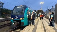 Am Kieler Bahnhof stehen zwei Personen vor einem Akkuzug der Firma erixx Holstein. © NDR Foto: Tobias Gellert