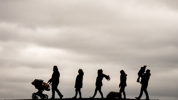 Eine mehrköpfige Familie aus Delmenhorst geht mit Kind und Kegel am Ostersonntag bei bedecktem Himmel im Kurort Dangast am Jadebusen spazieren. © picture alliance/dpa Foto: Mohssen Assanimoghaddam