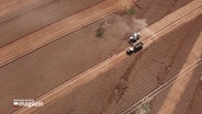 Eine Drohnenaufnahme zeigt einen Mähdrescher bei der Ernte auf einem Getreidefeld. © NDR 