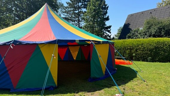 Ein buntes Zirkuszelt steht auf einer Wiese. © Karen Münster Foto: Karen Münster