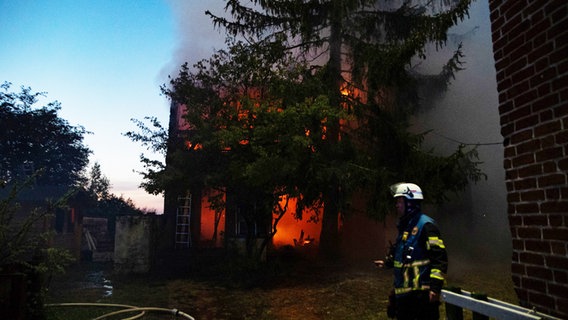 Ein Feuerwehrmann steht vor einem brennenden Schuppen © Arne Jappe Foto: Arne Jappe