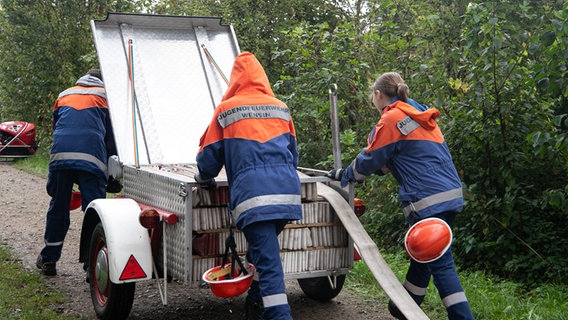 Mitglieder der Feuerwehr Ovendorf rollen eine Löschschlau ab. © NDR Foto: Marina Heller