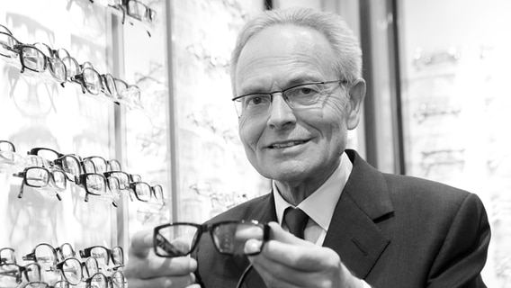 Günther Fielmann, ehemaliger Vorstandsvorsitzender der Fielmann AG, steht vor einem Brillenregal. © picture alliance Foto: Bodo Marks