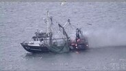 Ein brennender Fischkutter treibt auf offener See. © dpa-Bildfunk 