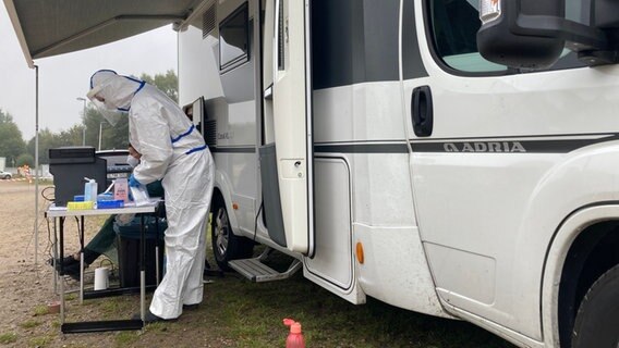 Eine Mitarbeiterin der Kassenärztlichen Vereinigung steht auf einem Parkplatz, um mehrere Schulklassen - insgesamt rund 160 Menschen - auf Corona zu testen. © dpa-Bildfunk Foto:  Birgitta von Gyldenfeldt
