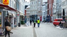 Kontrolleure laufen durch die leere Flensburger Innenstadt.