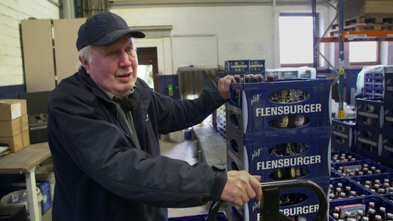Ein älterer Herr transportiert Kisten der Flensburger Brauerei. © NDR 
