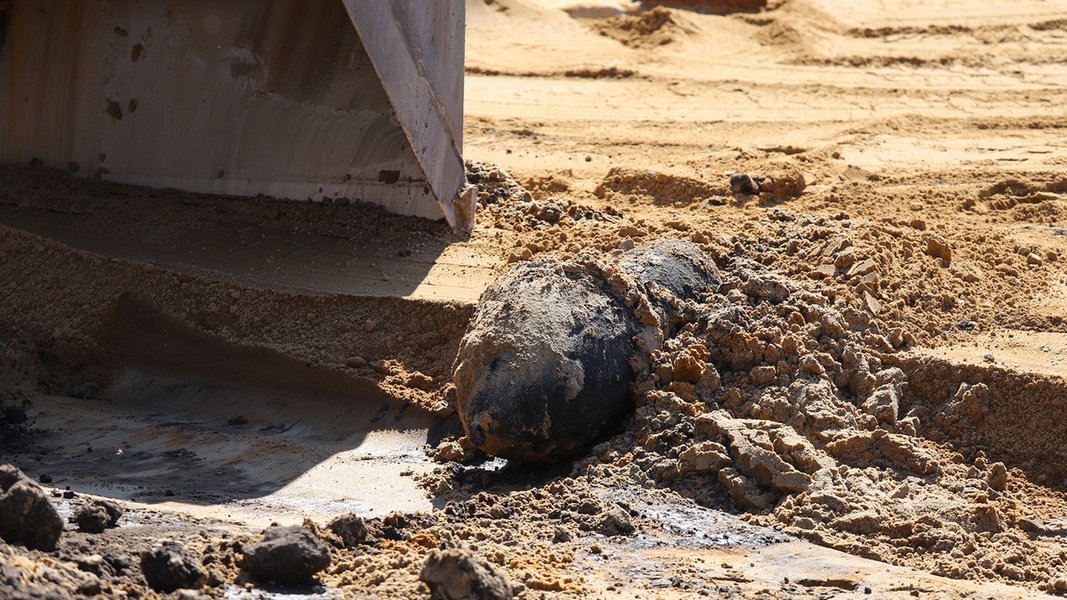 Ein Blindgänger einer Fliegerbombe liegt auf einem Platz mit Sand