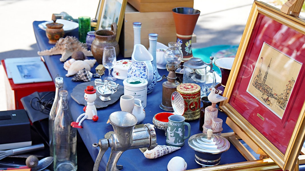 Diverse Gegenstände stehen auf einem Tisch auf einem Flohmarkt.