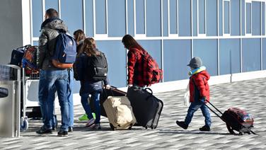 Eine fünf-köpfige Flüchtlingsfamilie betritt für die freiwillige Ausreise mit ihrem Gepäck einen Flughafen. © dpa - Bildfunk Foto: Uwe Zucchi