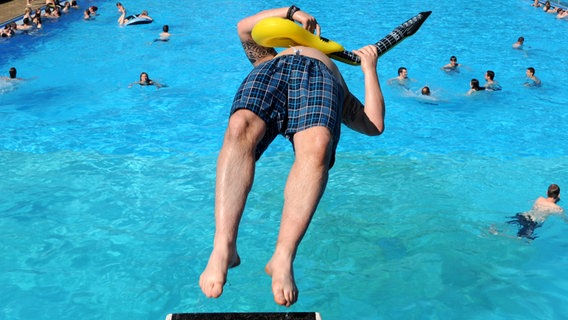 Eine Person springt rückwärts in ein Freibad. © picture alliance / dpa Foto: Carsten Rehder