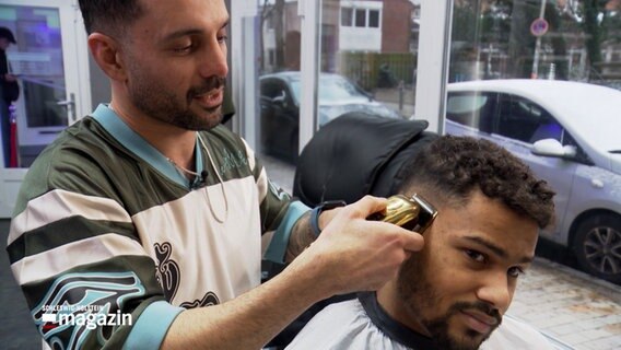 Ein Friseur schneidet einem Kunden die Haare. © NDR 