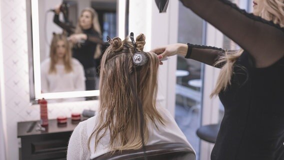 Eine Friseurin kämmt und föhnt einer Kundin die Haare. © picture alliance / imageBROKER Foto: Oleksandr Latkun