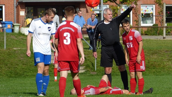 Ein Fußballspieler liegt auf dem Boden, während der Schiedsrichter ein Handzeichen gibt.  Foto: Petra Bojens