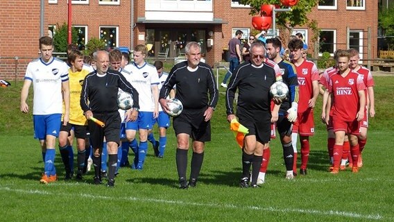 Fußballmannschaften und Schiedsrichter betreten das Spielfeld.  Foto: Petra Bojens