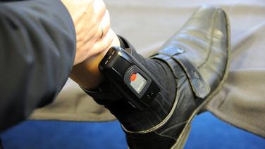 Elektronische Fußfessel an einem Bein © +++(c) dpa - Bildfunk+++ Fotograf: Carsten Rehder