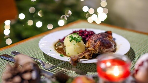 Eine Portion Gänsekeule mit Rotkraut und Klößen steht auf einem Tisch in einem Restaurant. © picture alliance Foto: Jan Woitas