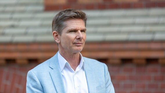 FDP-Politiker Heiner Garg steht vor einer Steinwand. © NDR Foto: Janis Röhlig