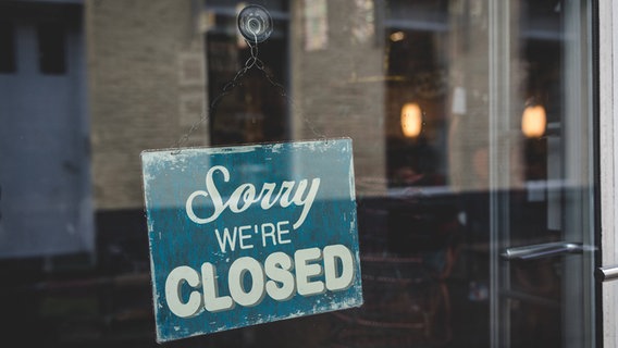 Hinter einer Glasscheibe hängt ein Schild mit der Aufschrift: "Sorry we're closed" © IMAGO Foto: Bihlmayerfotografie