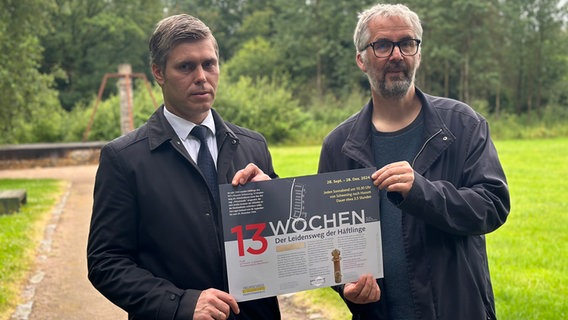 Zwei Männer halten eine Tafel in den Händen mit der Aufschrift: "13 Wochen - Der Leidensweg der Häftlinge". © NDR Foto: Jörn Zahlmann