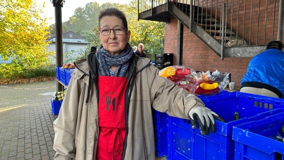Eine Frau steht vor einigen Kisten mit Lebensmitteln. © NDR Foto: Johannes Tran