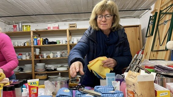 Eine Frau packt Lebensmittel und Putzlappen ein. © NDR Foto: Ole Wackermann