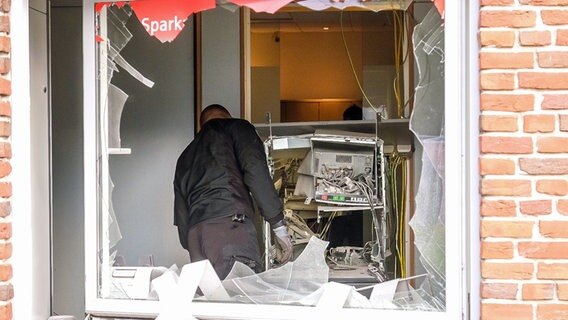 Ein Polizeibeamter begutachtet den stark beschädigten Geldautomaten. © Nordpresse Foto: Heiko Thomsen