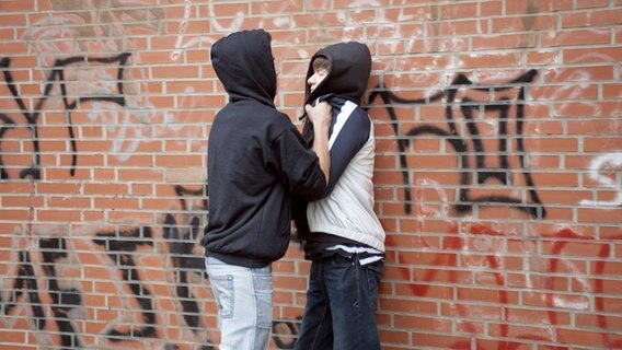 Ein Teenager drückt einen kleineren gewaltsam gegen eine Wand. © imago/imagebroker 