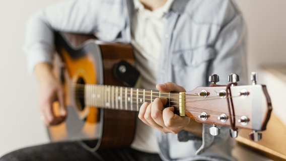 Eine Person spielt auf einer Gitarre. © imago images / Panthermedia 