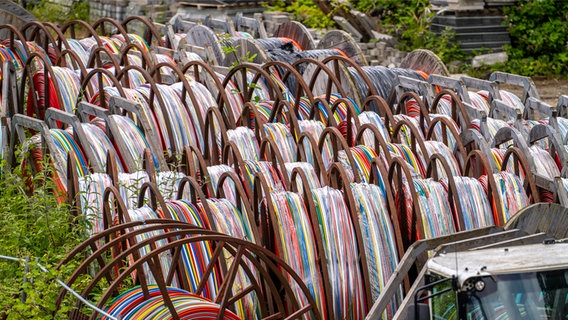 Kabeltrommeln mit Lehrrohren für Glasfaserkabel, auf einem Lagerhof. © IMAGO Foto: Jochen Tack