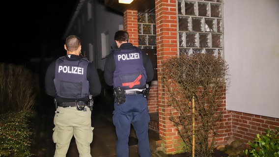 Zwei Polizeibeamte stehen vor dem Eingang eines Hauses. © Westküstennews Foto: Florian Sprenger