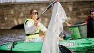 Eine "Green Kayak" Fahrerin hält einen Plastikmüllbeutel in die Kamera. © Green Kayak 