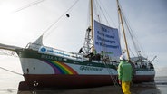Ein klassisches Segelschiff mit einem großen Banner zwischen seinen zwei Segeln. Der Banner trägt die Aufschrift "DEA - Keine neuen Ölbohrungen im Wattenmeer! Greenpeace" © dpa-Bildfunk Foto: Christian Charisius