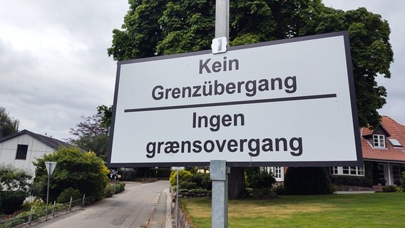 Eine weißes Schild mit der Aufschrift "Kein Grenzübergang" in Deutsch und Dänisch hängt an einer Straße in Niehuus. © NDR Foto: Peer-Axel Kroeske