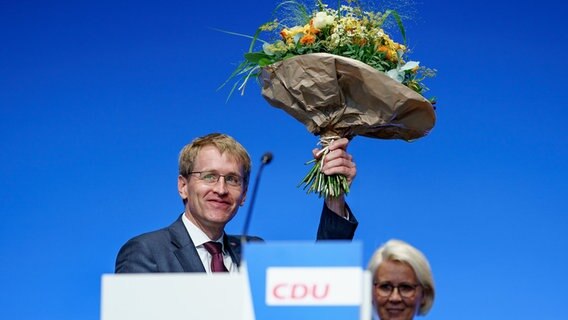 Daniel Günther (CDU) hält beim Landesparteitag der CDU Schleswig-Holstein nach seiner Wiederwahl zum Landesvorsitzenden einen Blumenstrauss in der Hand.  Foto: Axel Heimken