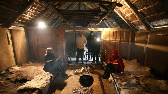 Besucher in einem originalgetreu hergerichteten und ausgestatteten Haus in der Wikingersiedlung Haithabu. Besucher in einem originalgetreu hergerichteten und ausgestatteten Haus in der Wikingersiedlung Haithabu. © dpa Foto: Carsten Rehder